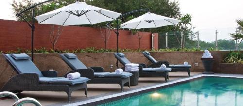 a group of chairs and umbrellas next to a pool at Vivanta Guwahati in Guwahati