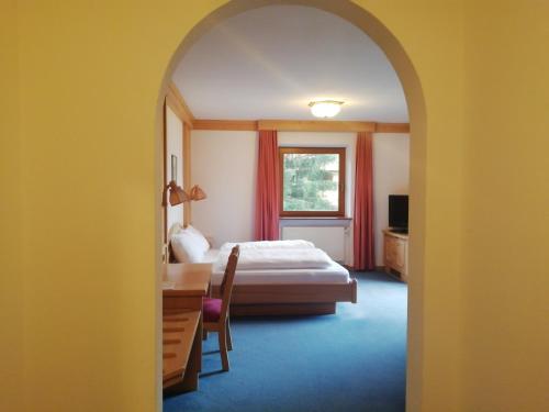 una camera con letto, scrivania e finestra di Sport Hotel Wildgall a Anterselva di Mezzo