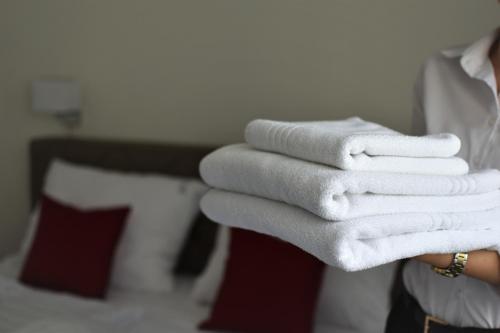 una persona che tiene in mano una pila di asciugamani bianchi di Hotel Slavija Banja Luka a Banja Luka