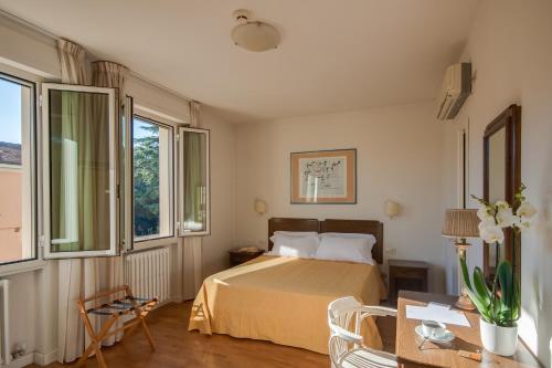 a bedroom with a bed and a table and windows at Hotel La Pace in Pontedera