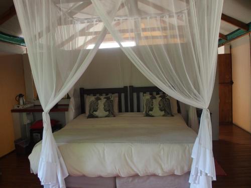 a bedroom with a canopy bed with white curtains at Lion Tree Top Lodge in Guernsey Nature Reserve