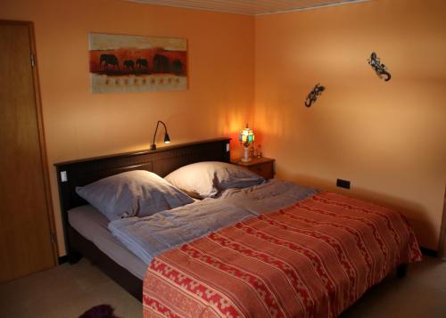 ein Schlafzimmer mit einem Bett mit einer roten Decke und einer Lampe in der Unterkunft Ferienwohnung Frankenwald in Naila