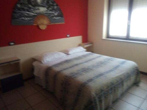 um quarto com uma cama com uma parede vermelha em affitacamere zimmer nadia em Chiuppano