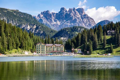 a hotel on a lake with mountains in the background at Grand Hotel Misurina in Misurina