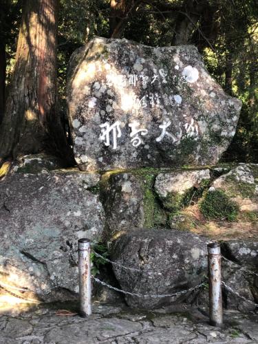 a rock with writing on it next to a tree at 浜の宮七福神 1棟貸し9名様までご利用できます in Nachikatsuura