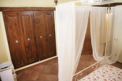 a bedroom with wooden cabinets and a white curtain at Casa De Ajala - B&B de Charme in Antica Dimora totalmente ristrutturata e dotata di tutti i confort Bagni privati Spazio living Patio esterno Ambienti climatizzati Degustazioni prodotti locali in Làconi