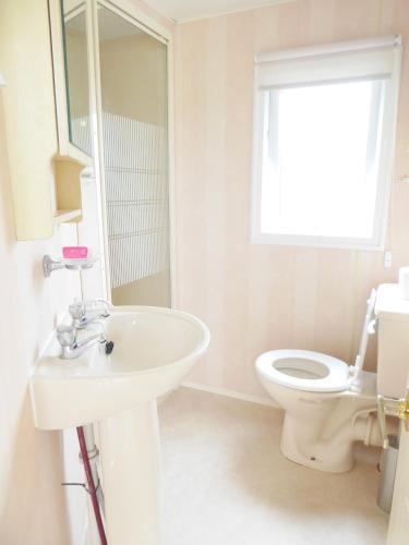 a white bathroom with a sink and a toilet at Beachside, Family-friendly, WiFi, 6 berth Caravan 226 in Ingoldmells