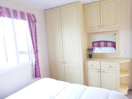 a bedroom with a bed and a cabinet and a window at Beachside, Family-friendly, WiFi, 6 berth Caravan 226 in Ingoldmells