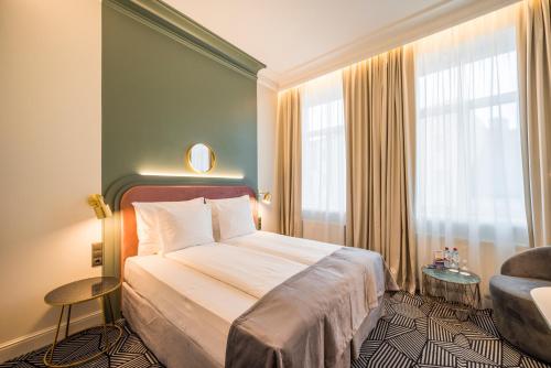 una habitación de hotel con una cama grande y una silla en Wellton Riverside SPA Hotel en Riga