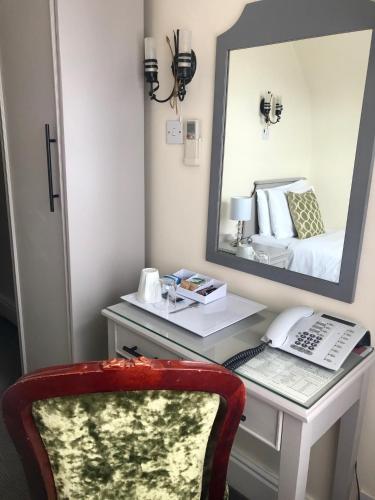 a bedroom with a desk with a mirror and a bed at Lensfield Hotel in Cambridge