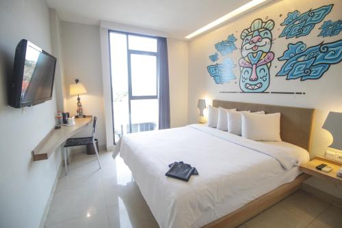 a bedroom with a bed and a desk and a television at Regantris Surabaya in Surabaya