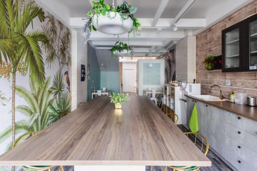 a large wooden table in a kitchen with plants at EATzzZ Hostel in Kaohsiung