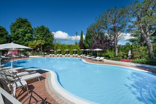 une grande piscine avec des chaises longues et des parasols dans l'établissement Park Residence Il Gabbiano, à Moniga del Garda