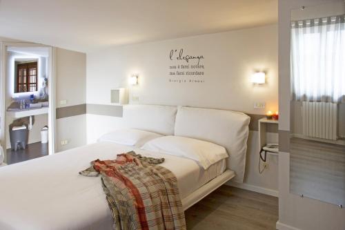 a white bed in a bedroom with a sign on the wall at Albergo Al Cacciatore Tortellinando in Valeggio sul Mincio