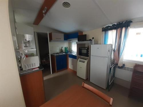 a kitchen with a white refrigerator and blue cabinets at Mobilhome in Les Mathes