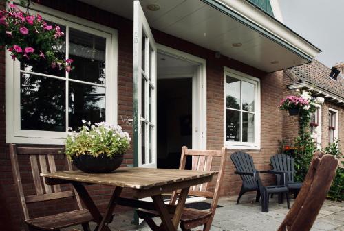 drewniany stół na patio z krzesłami i kwiatami w obiekcie Slapen bij Jesse w mieście Broek in Waterland