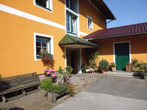 a yellow building with a bench and some flowers at Pension David in Puch bei Hallein