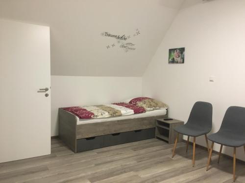 - une chambre avec un lit et deux chaises dans l'établissement Pension Seeblick Latzko, à Neusiedl am See