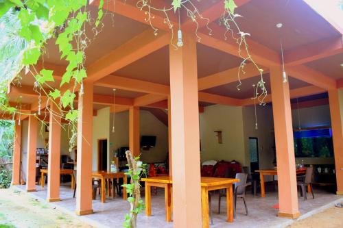 a patio with wooden tables and chairs and trees at LakeSide Cabana Tissamaharama in Tissamaharama