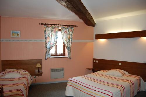 a bedroom with two beds and a window at Hotel du Donjon in Champlitte-et-le-Prélot