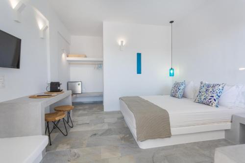 a white bedroom with a bed and a desk at Aspries Suites in Piso Livadi
