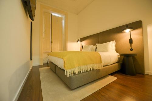 a bedroom with a bed with a yellow blanket on it at O Paço - exclusive accommodation in Tomar