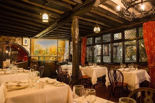 a restaurant with white tables and chairs and windows at Mermaid Inn in Rye