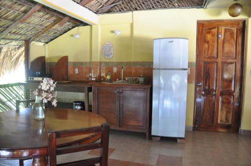 a kitchen with a white refrigerator and a table at Ananda Guest House Yoga & Meditación in Puerto Escondido