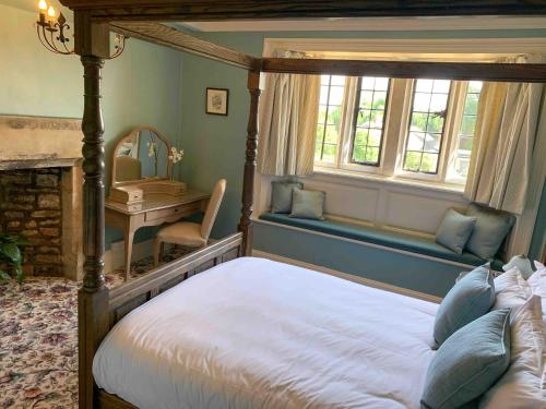 a bedroom with a canopy bed and a desk and window at Mortons Manor in Corfe Castle