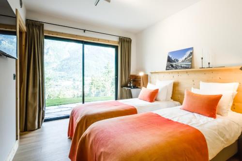 two beds in a room with a large window at Le Chalet Mont Blanc in Les Houches