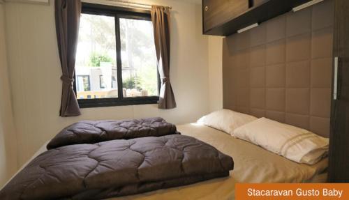1 cama grande en un dormitorio con ventana en Casa Mobile - Spiaggia e Mare Holiday Park, en Porto Garibaldi