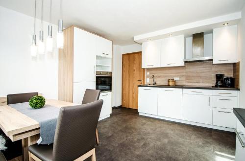 a kitchen with white cabinets and a wooden table at Apartment Mayerhofer in Mittersill