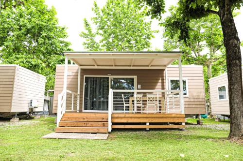 una casa pequeña con porche y terraza en Camping Rose, en Dormelletto