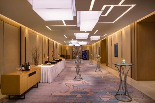 a lobby with a long hallway with tables and lights at Holiday Inn Tianjin Xiqing by IHG in Tianjin