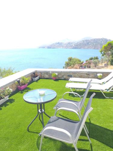 a patio with a table and chairs and the ocean at Aegean Blue in Panteli