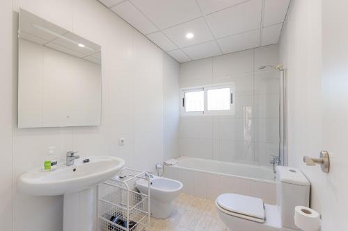 a white bathroom with a sink and a toilet and a tub at Chalet Bon Sol in El Campello