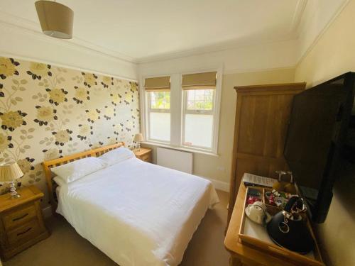 a bedroom with a white bed and a television at NORTHRISE RETREAT in Hastings