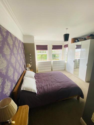 a bedroom with a bed with purple sheets and windows at NORTHRISE RETREAT in Hastings
