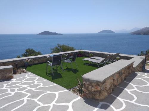 a patio with a table and chairs and the ocean at Aegean Blue in Panteli