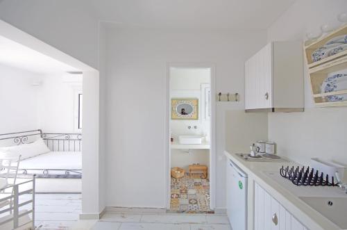 a kitchen with white cabinets and a bed in a room at Villa Katapoliani No.3 in Katapola