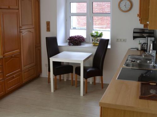 a kitchen with a white table and black chairs at Ferienwohnung Veischedetal im Sauerland in Lennestadt