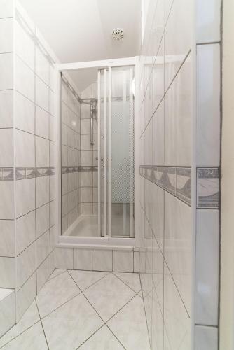 a white bathroom with a shower and a mirror at Pokoje gościnne Neptun in Ostrowo