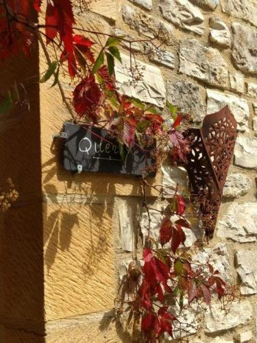 a sign on the side of a brick wall with flowers at La Lezardiere in Gourdon-en-quercy