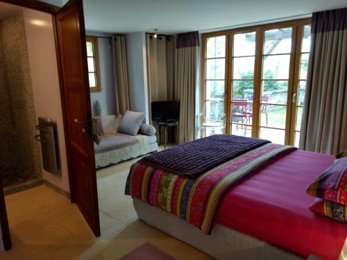 a bedroom with a bed and a couch and a window at La Lezardiere in Gourdon-en-quercy