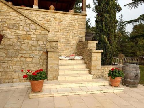 a stone building with stairs and two pots of flowers at La Lezardiere in Gourdon-en-quercy