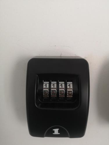 a black alarm clock sitting on a white wall at Apartamenty Lawendowy Zakątek 2 in Opole