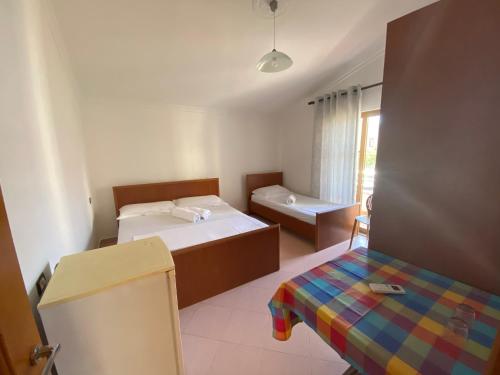 a bedroom with two beds and a table and a window at Guest House Lionel in Durrës