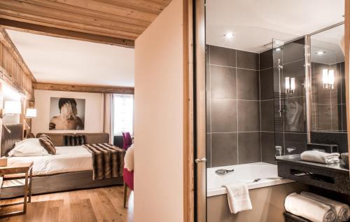 a bedroom with a bed and a bathroom with a shower at Au Coeur du Village in La Clusaz