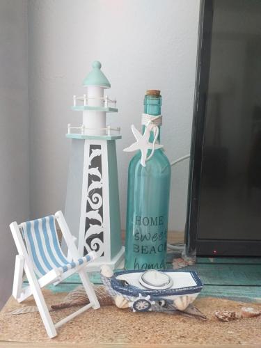 a bottle of water next to a beach chair and a lighthouse at Aegean Blue in Panteli