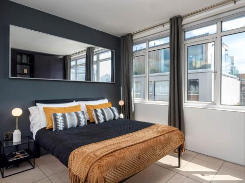 a bedroom with a bed with yellow pillows and windows at D8 - Hoxton Square Penthouse in London